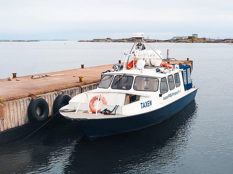 A small taxi boat docks at a pier surrounded by islands. 