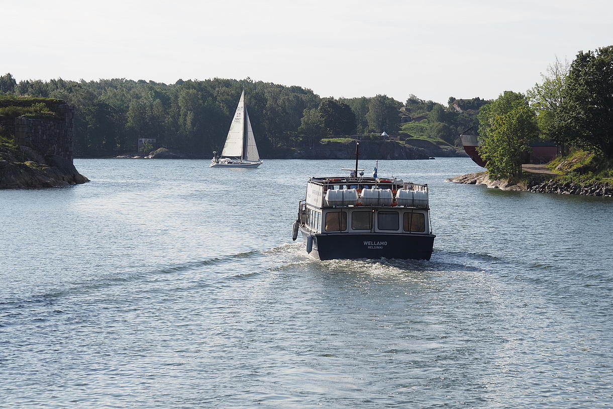 A boat sailing between the islands of the archipelago next to a sailboat.