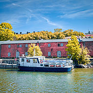 A boat in front of a stone house lying in the harbour in autumn.